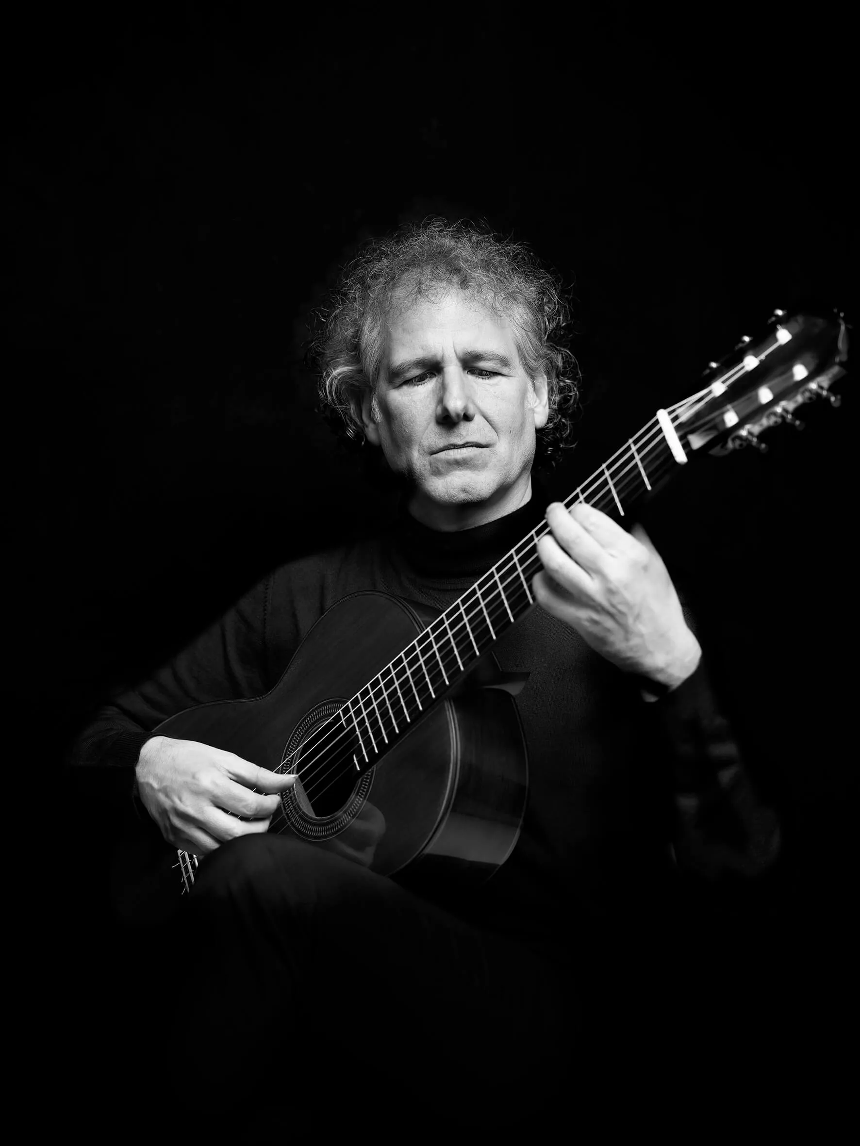 Alexander Swete playing the guitar with his eyes closed, black-and-white portrait
